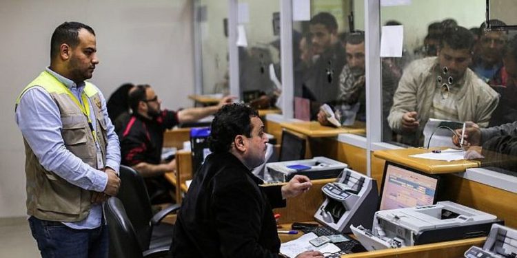 Los trabajadores de correos ayudan a los palestinos que llegaron a la oficina central de correos en la ciudad de Gaza el 26 de enero de 2019, para recibir ayuda financiera del gobierno de Qatar que se otorga a familias empobrecidas. (Mahmud Hams / AFP)