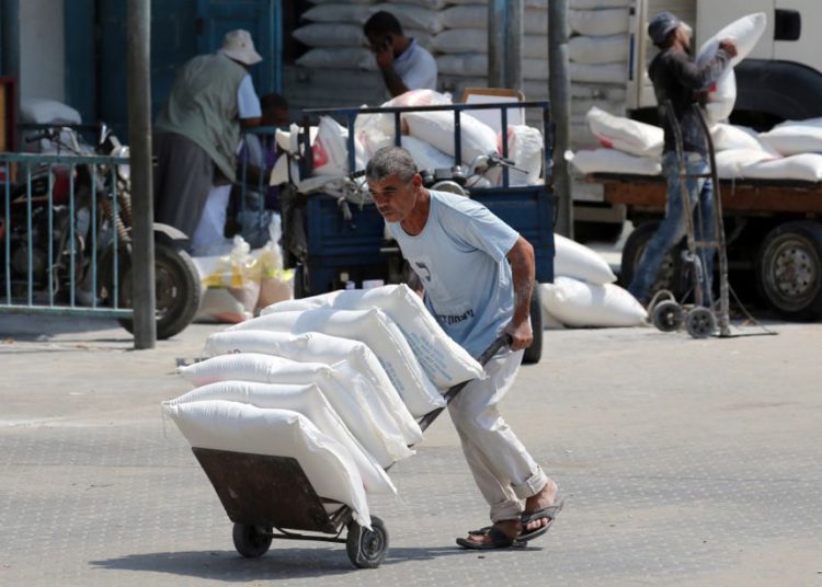 Un palestino empuja un carrito con bolsas de harina en un centro de distribución de ayuda administrado por el Organismo de Obras Públicas y Socorro de las Naciones Unidas (UNRWA) en Khan Younis, en el sur de la Franja de Gaza, 1 de septiembre de 2018 .. (crédito de foto: REUTERS / IBRAHEEM ABU MUSTAFA)