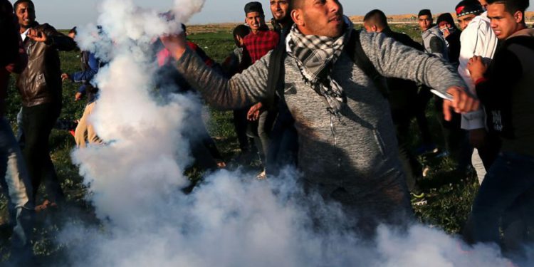 Un manifestante palestino devuelve un bote de gas lacrimógeno disparado por tropas israelíes durante una protesta en la valla fronteriza entre Israel y Gaza, en el sur de la Franja de Gaza, enero 4,2019. (Crédito de la foto: IBRAHEEM ABU MUSTAFA / REUTERS)
