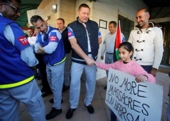 Una niña palestina le da la mano a un miembro de la Presencia Internacional Temporal en Hebrón (TIPH) durante una protesta contra la decisión del Primer Ministro israelí, Benjamin Netanyahu, de no renovar el mandato de TIPH, en Hebrón, el 30 de enero de 2019. Mussa Qawasma / Reuters