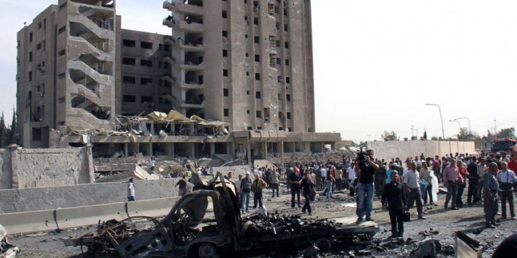 Foto ilustrativa de sirios reunidos frente a un edificio de inteligencia militar dañado donde explotaron dos bombas, en el barrio de Qazaz en Damasco, Siria, 10 de mayo de 2012. (Bassem Tellawi / AP)
