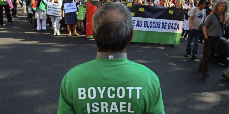 Los manifestantes gritan consignas durante un mitin en París, Francia, el 3 de junio de 2010, mientras se manifiestan contra el ataque de Israel contra un barco de ayuda con destino a Gaza; un hombre en primer plano lleva una camiseta que pide un boicot a Israel. (Jacques Brinon / AP)