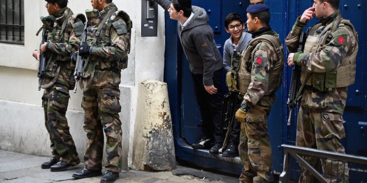 Ilustrativo: los niños miran desde una puerta mientras soldados armados patrullan fuera de una escuela en el barrio judío del distrito de Marais en París, 13 de enero de 2015. (Jeff J. Mitchell / Getty Images / vía JTA)