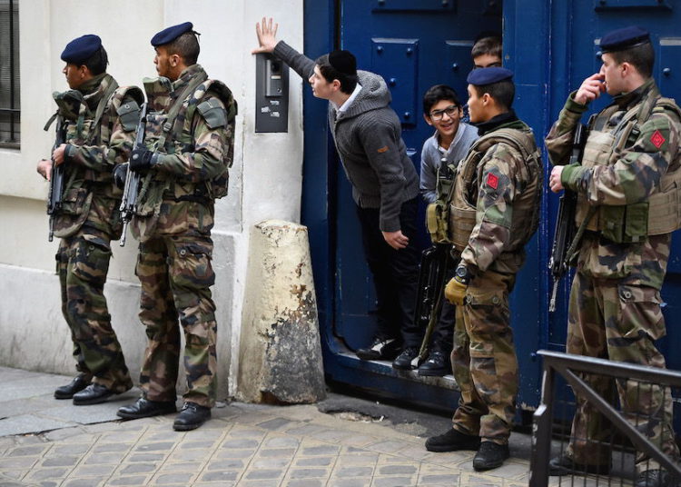 Ilustrativo: los niños miran desde una puerta mientras soldados armados patrullan fuera de una escuela en el barrio judío del distrito de Marais en París, 13 de enero de 2015. (Jeff J. Mitchell / Getty Images / vía JTA)