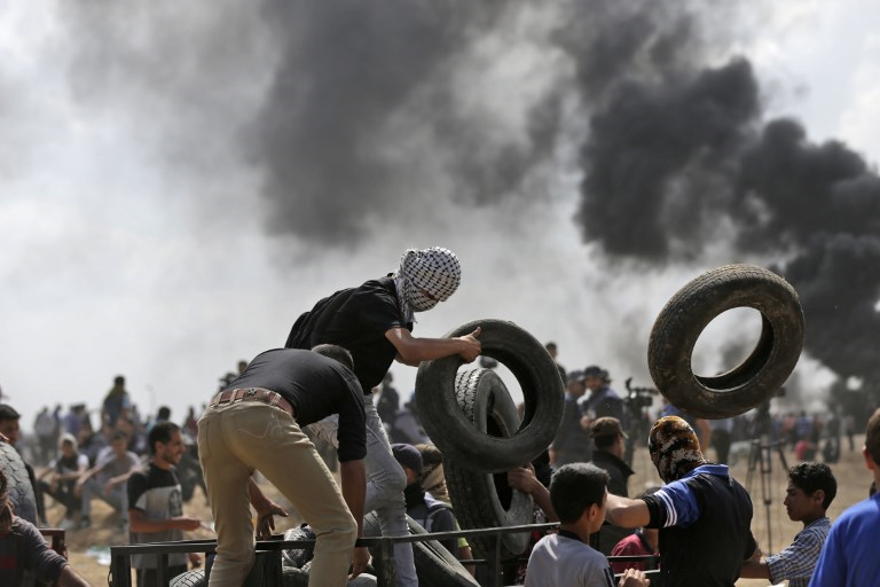 Los terroristas palestinos queman neumáticos cerca de la frontera entre Gaza e Israel, al este de la ciudad de Gaza, durante los ataques por la inauguración de la embajada de Estados Unidos en Jerusalén, 14 de mayo de 2018 (AFP Photo / Mahmud Hams)