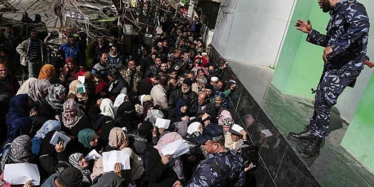 Las fuerzas de seguridad leales a Hamas organizan una línea fuera de la oficina central de correos en la ciudad de Gaza el 26 de enero de 2019, mientras los palestinos se reúnen para recibir ayuda financiera de Qatar. (Mahmud Hams / AFP)
