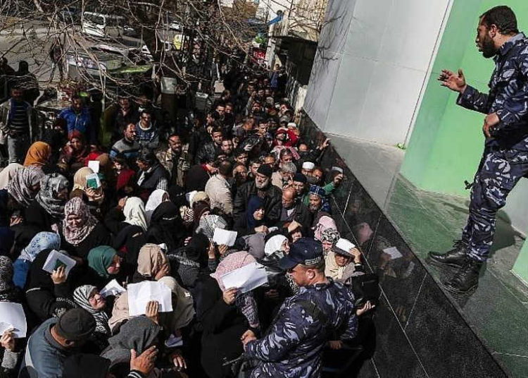 Las fuerzas de seguridad leales a Hamas organizan una línea fuera de la oficina central de correos en la ciudad de Gaza el 26 de enero de 2019, mientras los palestinos se reúnen para recibir ayuda financiera de Qatar. (Mahmud Hams / AFP)