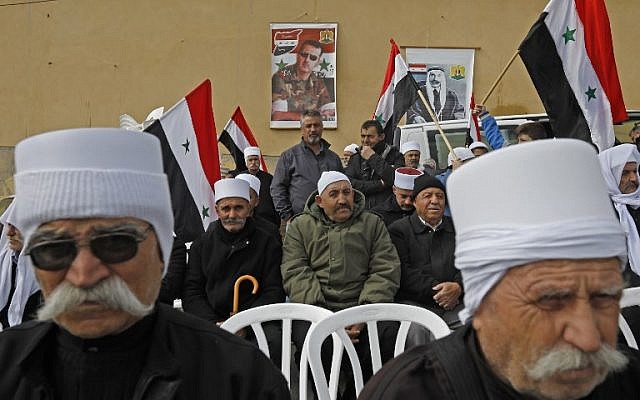 Los retratos del presidente Bashar al-Assad (C) y del difunto líder árabe druso Sultan al-Atrash (R) se ven en el fondo durante una protesta en Madjal Shams el 14 de febrero de 2019 (JALAA MAREY / AFP)