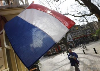 Una mujer pasa junto a una bandera nacional, el día antes de una elección general, en Delft, Países Bajos, 14 de marzo de 2017 .. (crédito de foto: REUTERS)