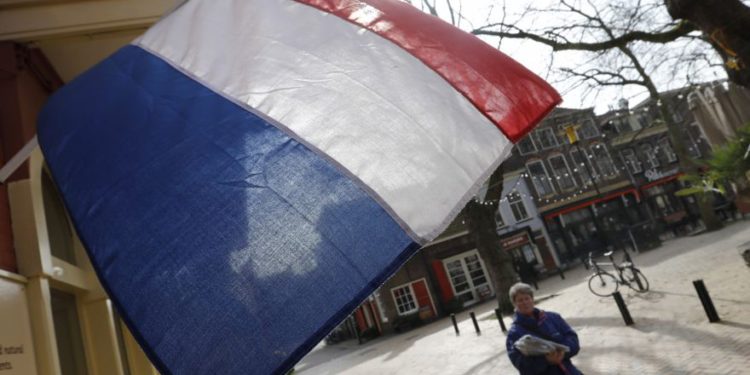 Una mujer pasa junto a una bandera nacional, el día antes de una elección general, en Delft, Países Bajos, 14 de marzo de 2017 .. (crédito de foto: REUTERS)