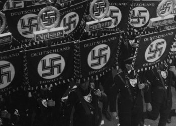 Los miembros de las SS llevan banderas con una esvástica y nombres de estados y ciudades alemanas mientras marchan hacia el ayuntamiento de Nuremberg, Alemania, el 10 de septiembre de 1935, para inaugurar la convención del Partido Nacional Socialista de los Trabajadores Alemanes. (Foto AP)