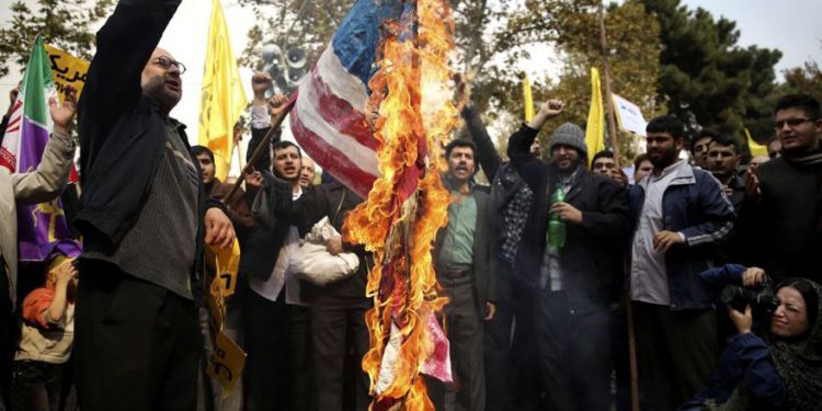 Los manifestantes iraníes queman una bandera estadounidense durante un mitin anual antiamericano en Teherán, Irán, el lunes 4 de noviembre de 2013. (Ebrahim Noroozi / AP)