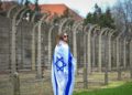 Una mujer envuelta en una bandera israelí en la Marcha de los Vivos en el campamento de Auschwitz-Birkenau en Polonia, 11 de abril de 2018 (Yossi Zeliger / Flash 90)