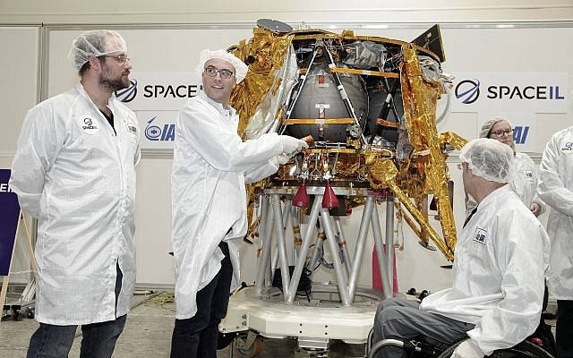 Yariv Bash, a la derecha, Yonatan Winetraub, en medio, y Kfir Damari, los fundadores de SpaceIL, insertando una cápsula del tiempo en la nave espacial Beresheet, 17 de diciembre de 2018 (Yoav Weiss)