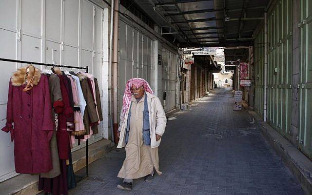 Un hombre árabe camina frente a tiendas cerradas después de que se convocó una huelga para protestar contra la ley de seguridad social propuesta por la Autoridad Palestina, en la ciudad de Hebrón, el 15 de enero de 2019. (HAZEM BADER / AFP)