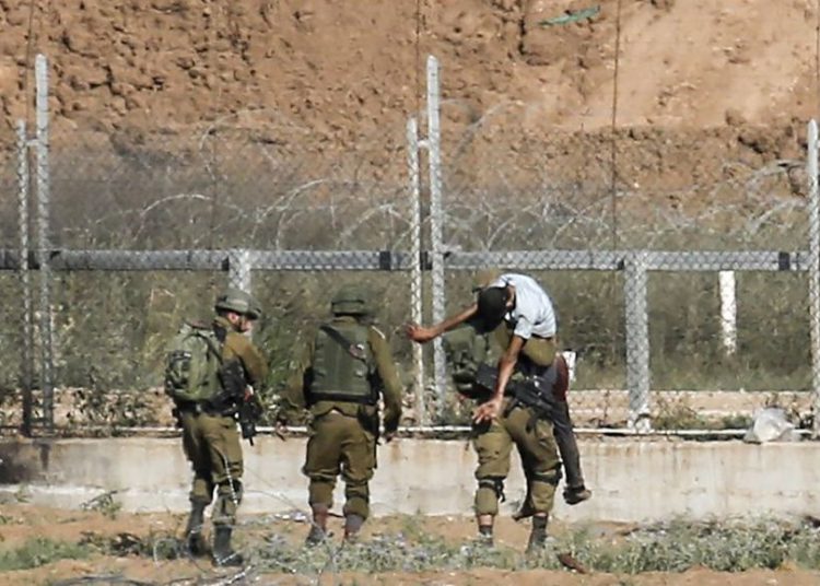 Ilustrativo: los soldados israelíes se llevan a un palestino herido que, según el ejército, intentó romper la cerca fronteriza al este de Jabaliya en el norte de la Franja de Gaza el 27 de junio de 2018. (Said Khatib / AFP)