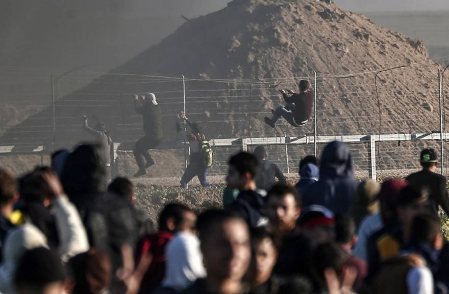 Los terroristas musulmanes escalan la valla fronteriza con Israel durante los ataques cerca de la valla a lo largo de la frontera con Israel, al este de la ciudad de Gaza, el 8 de marzo de 2019. (Mahmud Hams / AFP)