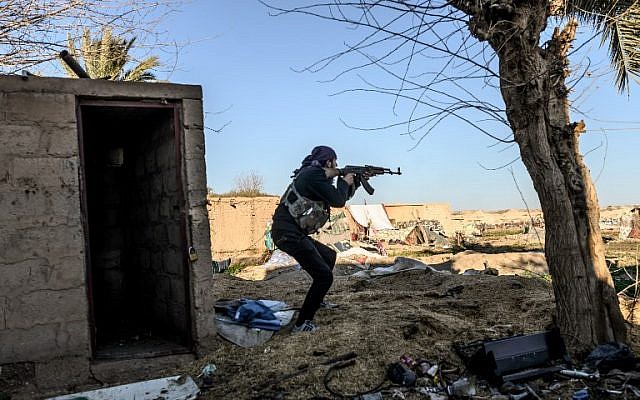 Un combatiente de las Fuerzas Democráticas Sirias (SDF) apunta con su rifle de asalto Kalashnikov después de ver a un hombre caminando hacia su posición en la ciudad de Baghouz, en la provincia siria oriental de Deir Ezzor, el 9 de marzo de 2019. (BULENT KILIC / AFP)