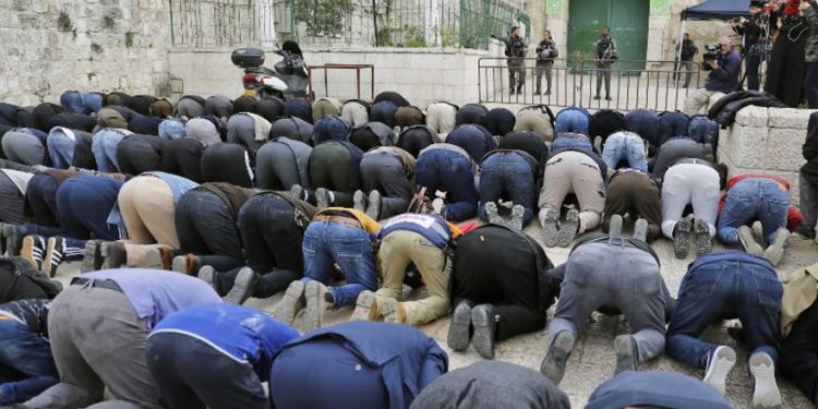Los fieles musulmanes palestinos rezan frente a una barrera después de que la policía fronteriza israelí cerró una de las entradas del complejo del Monte del Templo en la ciudad vieja de Jerusalem el 12 de marzo de 2019. (Ahmad Gharabli / AFP)