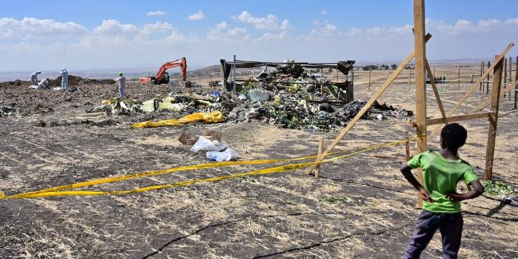 Un niño parece que los investigadores forenses peinan el suelo en busca de pruebas de ADN cerca de una pila de escombros retorcidos del avión en el lugar del accidente de un avión Boeing 737 MAX operado por las vías aéreas etíopes el 16 de marzo de 2019 en la aldea de Hama Quntushele cerca de Bishoftu en la región de Oromia. (TONY KARUMBA / AFP)