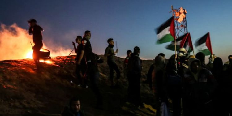 Los terroristas palestinos participan en una manifestación nocturna cerca de la cerca a lo largo de la frontera con Israel el 19 de marzo de 2019. AFP