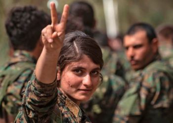Una luchadora de las Fuerzas Democráticas Sirias, liderada por los kurdos y respaldada por Estados Unidos, muestra el símbolo de la victoria mientras celebra la eliminación del último bastión de ISIS, Deir Ezzor, Siria, 23 de marzo de 2019. AFP