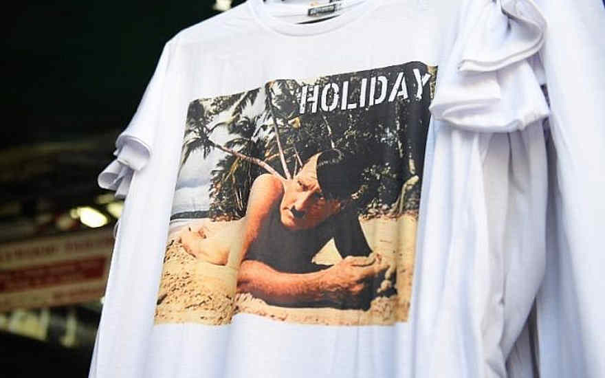Esta foto, tomada el 27 de febrero de 2019, muestra una camiseta con una foto de un Adolf Hitler desnudo en una playa en venta en un mercado callejero para turistas en Bangkok. (Lillian SUWANRUMPHA / AFP)