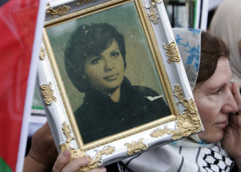 Una mujer sostiene una foto del guerrillero palestino Dalal al-Mughrabi cuando un convoy que transporta su cuerpo pasa por la carretera del aeropuerto de Beirut el 17 de julio de 2008. El cuerpo de Mughrabi, quien murió mientras dirigía una redada de 1978 en Israel, fue entregado por Israel. como parte de un intercambio de prisioneros con Hezbollah .. (crédito de foto: SHARIF KARIM / REUTERS)
