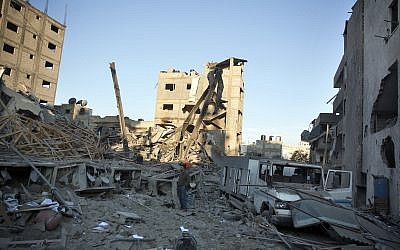 Los palestinos verifican el daño del edificio de la estación de televisión Al-Aqsa de Hamás, que fue golpeada por ataques aéreos israelíes en la ciudad de Gaza, 13 de noviembre de 2018. (AP / Khalil Hamra)