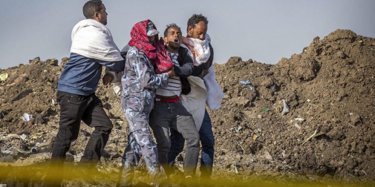 Un familiar afligido que perdió a su esposa en el accidente recibe ayuda de un miembro de las fuerzas de seguridad y otros en el lugar del accidente del Boeing 737 de Ethiopian Airlines, 8 de marzo de 2019. (AP / Mulugeta Ayene)