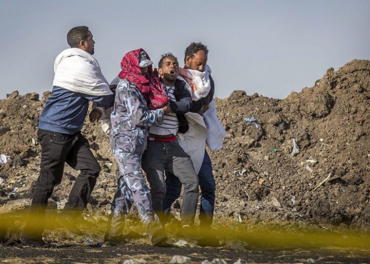 Un familiar afligido que perdió a su esposa en el accidente recibe ayuda de un miembro de las fuerzas de seguridad y otros en el lugar del accidente del Boeing 737 de Ethiopian Airlines, 8 de marzo de 2019. (AP / Mulugeta Ayene)