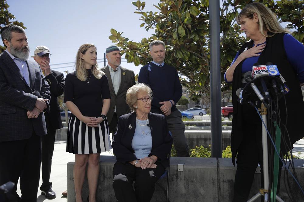 Eva Schloss, centro, la hermanastra de Ana Frank y sobreviviente del Holocausto, escucha a Charlene Metoyer, miembro de la junta del Distrito Escolar Unificado de Newport-Mesa durante una conferencia de prensa el jueves 7 de marzo de 2019, en Newport Beach, California. (AP / Jae C. Hong)