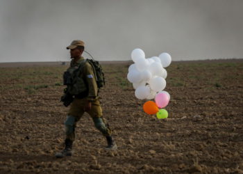 Ilustrativo. Un soldado israelí está parado cerca de globos lanzados por manifestantes palestinos de la Franja de Gaza que aterrizaron dentro de Israel el 19 de octubre de 2018. (Yossi Zamir / Flash90)