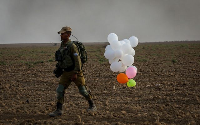 Ilustrativo. Un soldado israelí está parado cerca de globos incendiarios lanzados por terroristas palestinos de la Franja de Gaza que aterrizaron dentro de Israel el 19 de octubre de 2018. (Yossi Zamir / Flash90)