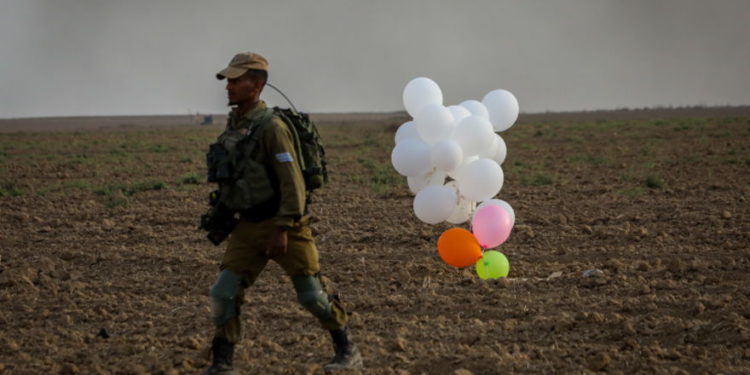Ilustrativo. Un soldado israelí está parado cerca de globos lanzados por manifestantes palestinos de la Franja de Gaza que aterrizaron dentro de Israel el 19 de octubre de 2018. (Yossi Zamir / Flash90)