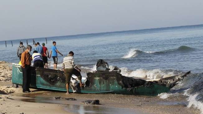 Pescadores árabes inspeccionan su barco pesquero destruido que fue arrastrado hacia la costa, cerca de la ciudad de Rafah, en el sur de la Franja de Gaza, el 26 de marzo de 2014. (Crédito de la foto: Said Khatib / AFP)