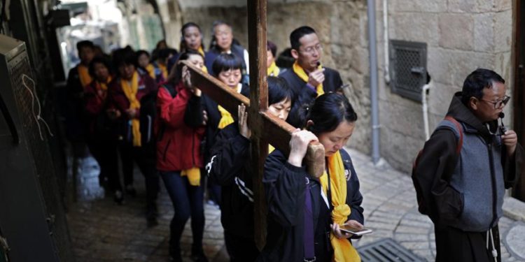 Los peregrinos católicos chinos llevan una cruz de madera a lo largo de la Via Dolorosa en la Ciudad Vieja de Jerusalem durante la procesión del Viernes Santo el 19 de abril de 2019. (Thomas Coex / AFP)