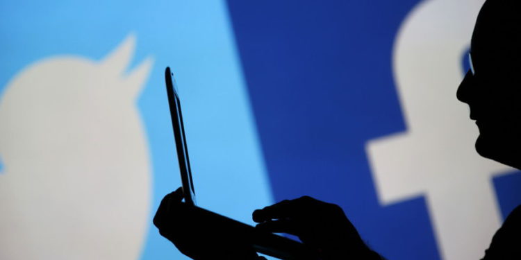 Un hombre está recortado contra una pantalla de video con un Twitter y un logotipo de Facebook. (Crédito de la foto: DADO RUVIC / REUTERS)