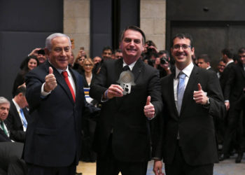 Benjamin Netanyahu (R) y Jair Bolsanaro (C) aprueban en un foro de negocios en el Hotel David Citadel de Jerusalén, el 2 de abril de 2019. (Crédito de la foto: AMOS BEN-GERSHOM / GPO)