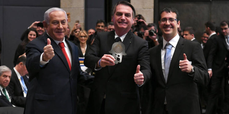 Benjamin Netanyahu (R) y Jair Bolsanaro (C) aprueban en un foro de negocios en el Hotel David Citadel de Jerusalén, el 2 de abril de 2019. (Crédito de la foto: AMOS BEN-GERSHOM / GPO)