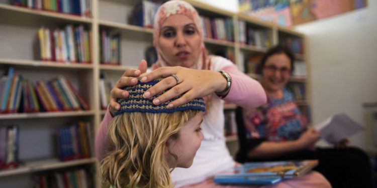 Alia Tunisi ajusta el casco de un estudiante, Mano a mano en la escuela bilingüe judía árabe, Jerusalén, 2014 .. (Crédito de la foto: RONEN ZVULUN / REUTERS)