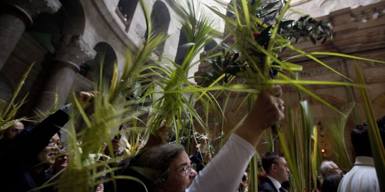 Monjes y fieles católicos reparten ramas de olivos en Jerusalem pese a las restricciones