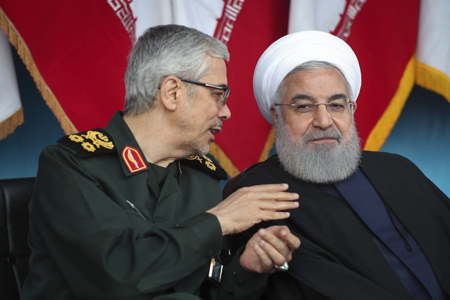 En esta foto publicada por el sitio web oficial de la oficina de la Presidencia iraní, el presidente Hassan Rouhani, a la derecha, escucha al jefe del Estado Mayor General de las Fuerzas Armadas, general Mohammad Hossein Bagheri, durante el desfile del ejército que conmemora el Día Nacional del Ejército frente al Santuario del fallecido fundador revolucionario, el Ayatolá Jomeini, a las afueras de Teherán, Irán, el 18 de abril de 2019. (Oficina de la Presidencia iraní a través de AP)