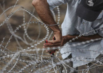 Ilustrativo. Un hombre palestino usa cortadores de alambre en una cerca de alambre de púas a lo largo de la frontera de Gaza con Israel el, 4 de mayo de 2018. (Wissam Nassar / Flash90 / File)