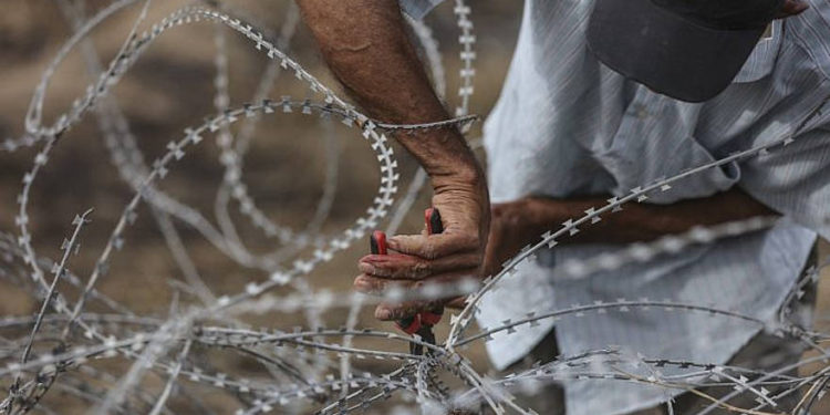 Ilustrativo. Un hombre palestino usa cortadores de alambre en una cerca de alambre de púas a lo largo de la frontera de Gaza con Israel el, 4 de mayo de 2018. (Wissam Nassar / Flash90 / File)