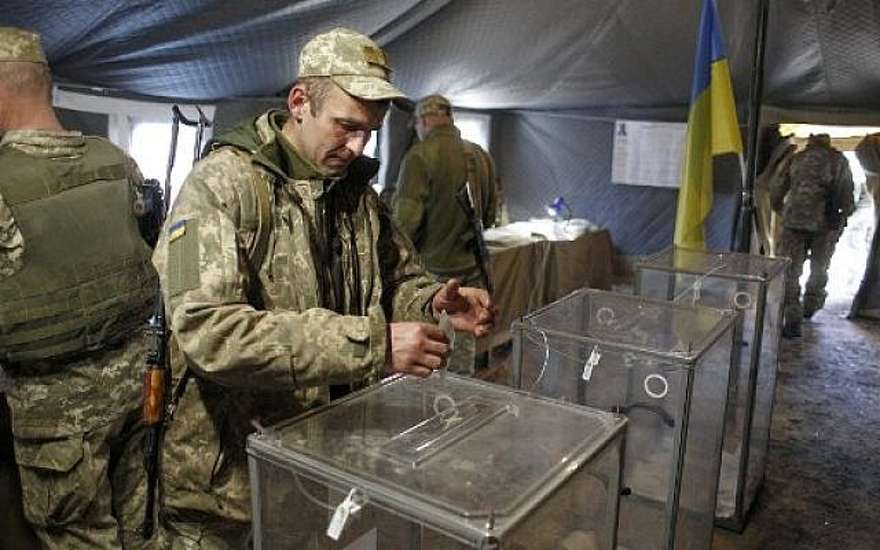 Un militar ucraniano emite su voto en una mesa electoral en la línea del frente con separatistas respaldados por Rusia en la ciudad de Zolote, región de Lugansk, durante la segunda vuelta de las elecciones presidenciales de Ucrania el 21 de abril de 2019. (Anatolii STEPANOV / AFP)