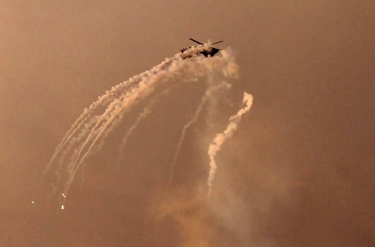 Un helicóptero israelí dispara bengalas sobre la Franja de Gaza horas después de que un cohete del enclave palestino impactara en una casa cerca de Tel Aviv e hiriera a siete personas, lo que provocó temores de una escalada grave, el 25 de marzo de 2019. (Mohammed Abed / AFP)