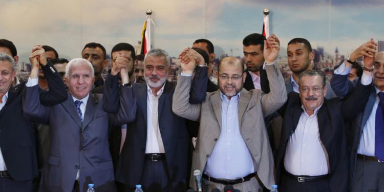 El funcionario de Fatah, Azzam Al-Ahmed (2º L), el jefe del gobierno de Hamas, Ismail Haniyeh (3º L) y el líder de Hamas, Moussa Abu Marzouq (4º L), se toman de las manos después de anunciar un acuerdo de reconciliación en la ciudad de Gaza el 23 de abril de 2014 El grupo islamista con sede en Gaza Hamas y el presidente Mahmoud A. (crédito de foto: SUHAIB SALEM / REUTERS)