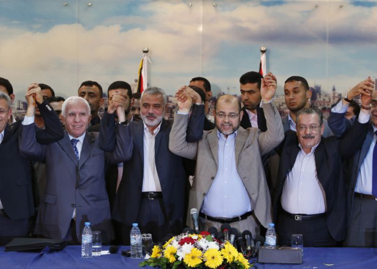 El funcionario de Fatah, Azzam Al-Ahmed (2º L), el jefe del gobierno de Hamas, Ismail Haniyeh (3º L) y el líder de Hamas, Moussa Abu Marzouq (4º L), se toman de las manos después de anunciar un acuerdo de reconciliación en la ciudad de Gaza el 23 de abril de 2014 El grupo islamista con sede en Gaza Hamas y el presidente Mahmoud A. (crédito de foto: SUHAIB SALEM / REUTERS)