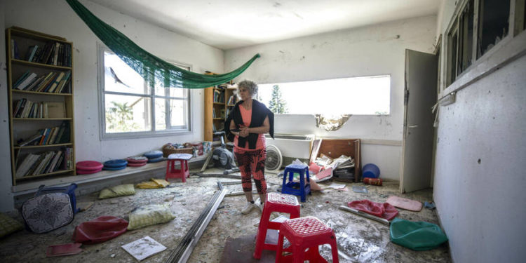 Una mujer observa el daño causado por un cohete lanzado desde Gaza que golpeó una casa en un moshav en Israel, cerca de la frontera con Gaza, el sábado 4 de mayo de 2019. (AP Photo / Tsafrir Abayov)